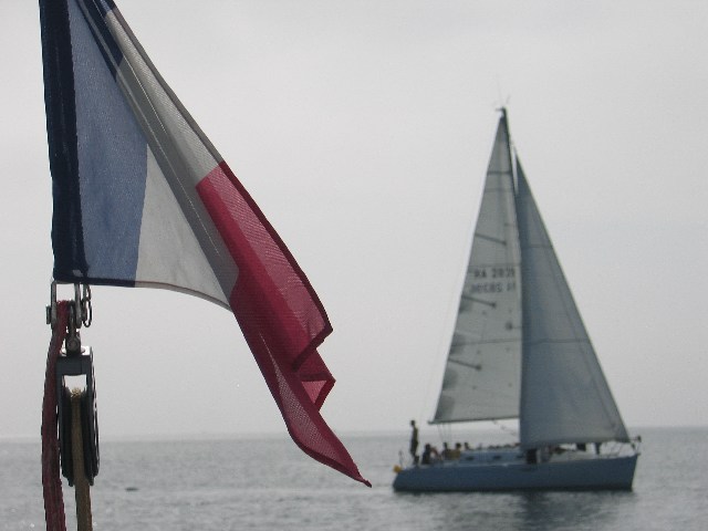 photo du pavillon français et un voilier en arrière plan