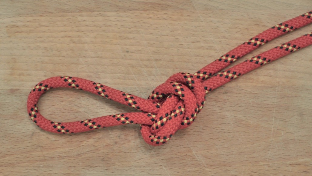 noeud de plein poing fait avec une corde rouge